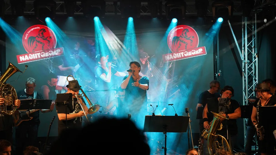 Nachtgeger mit Gesang und Bläsern im blauen Bühnenlicht